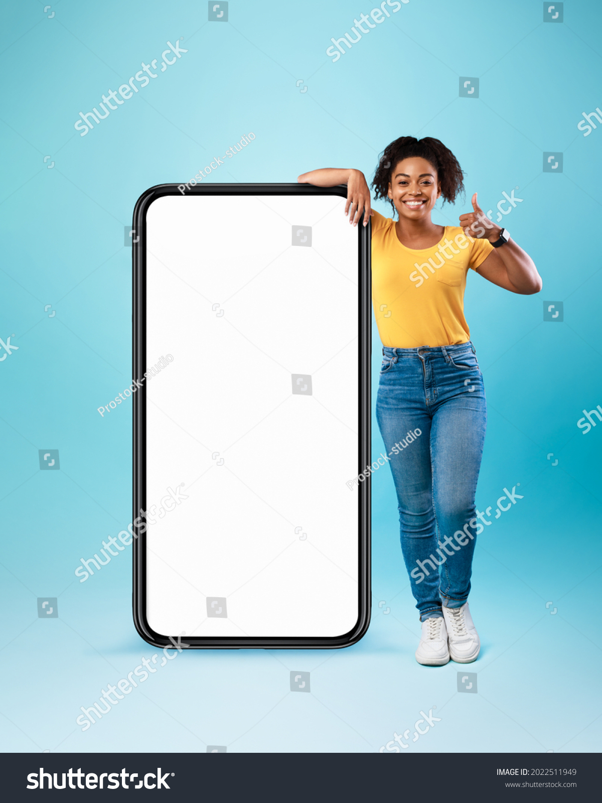 Mobile offer. Happy black lady leaning on huge cellphone with empty white screen, showing thumb up, recommending cool new app or website, offering space for your ad, mockup #2022511949
