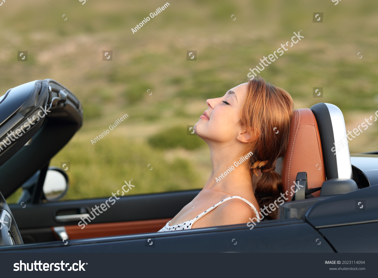 Profile of a woman breathing fresh air in a convertible car #2023114094