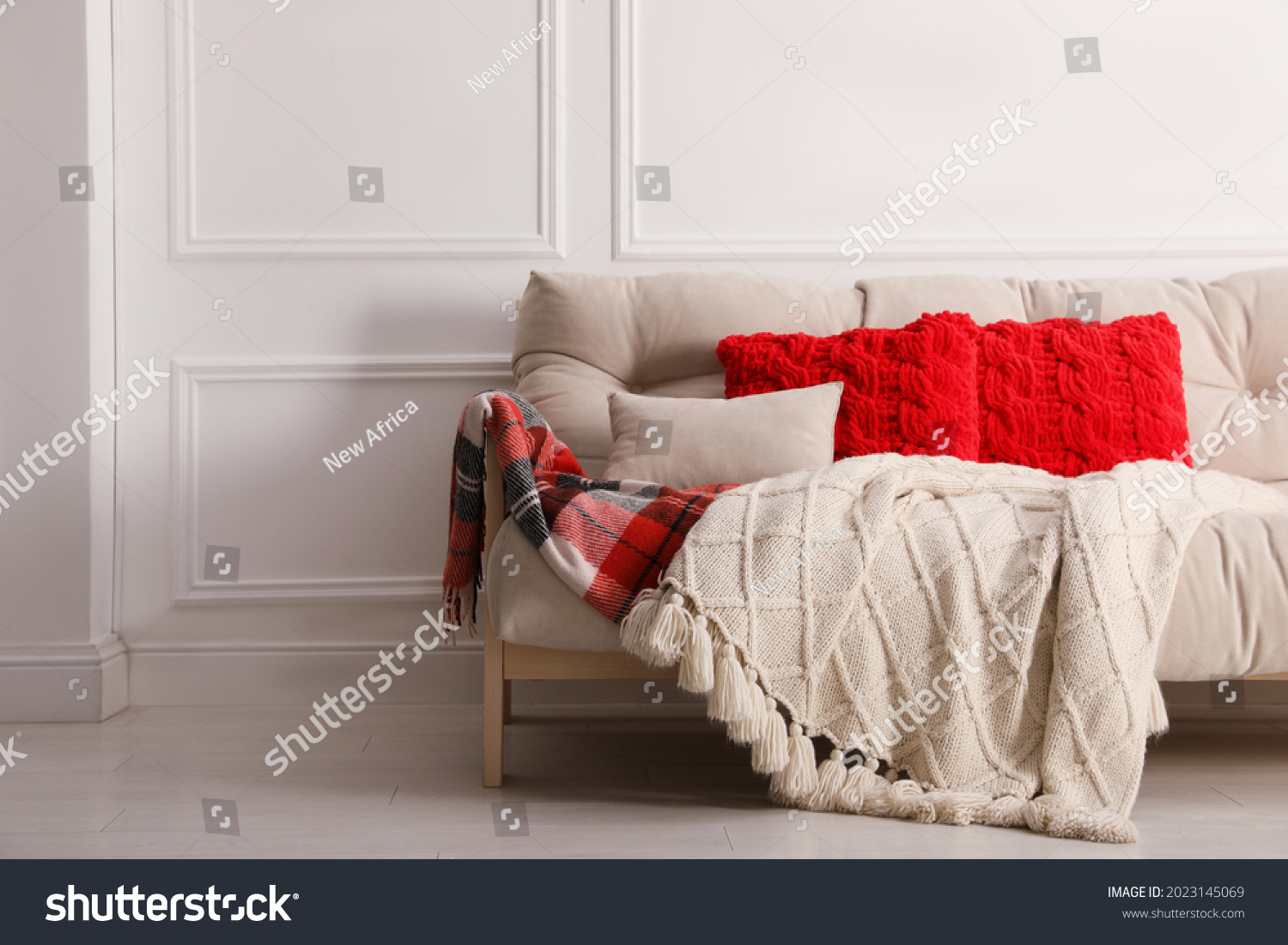 Different warm plaids and pillows on sofa in living room #2023145069