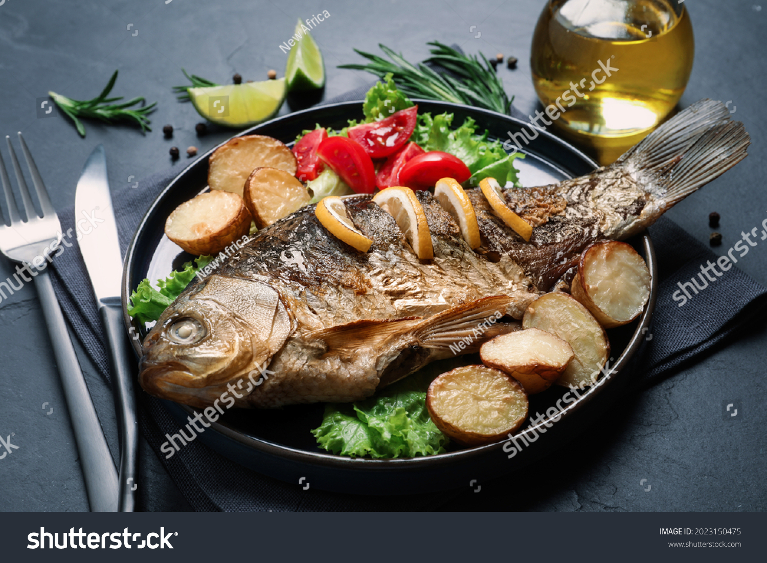 Tasty homemade roasted crucian carp served on black table. River fish #2023150475