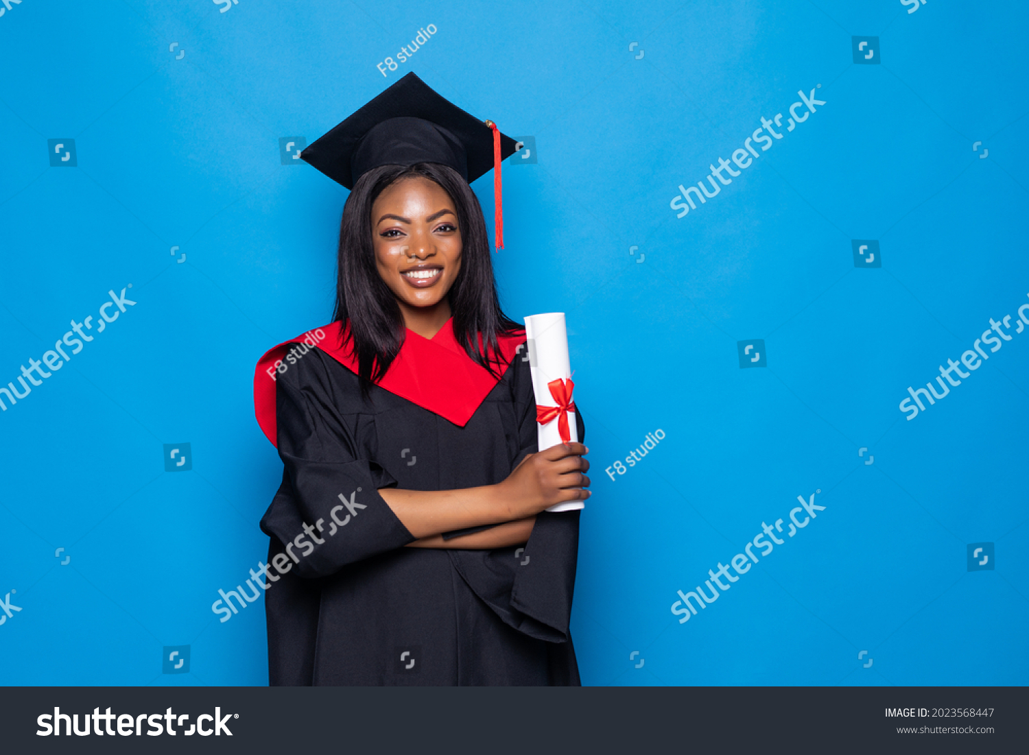 Beautiful african woman wearing a blue graduation gown holding a diploma and very happy and excited isolated on blue background #2023568447