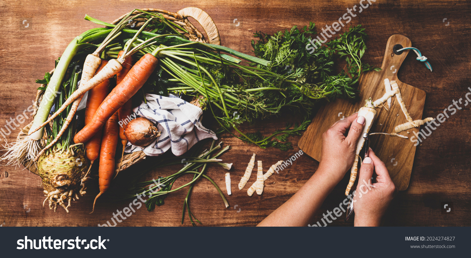 Cooking - chef's hands preparing fresh raw root vegetables (carrot, parsnip, celeriac, leek). Rustic kitchen scenery - wooden worktop captured from above (top view, flat lay).  #2024274827