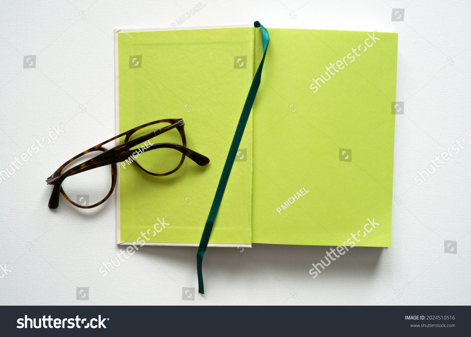 notebook with space for text, green paper, green bookmark, brown glasses, white background, canvas texture, top photo #2024510516