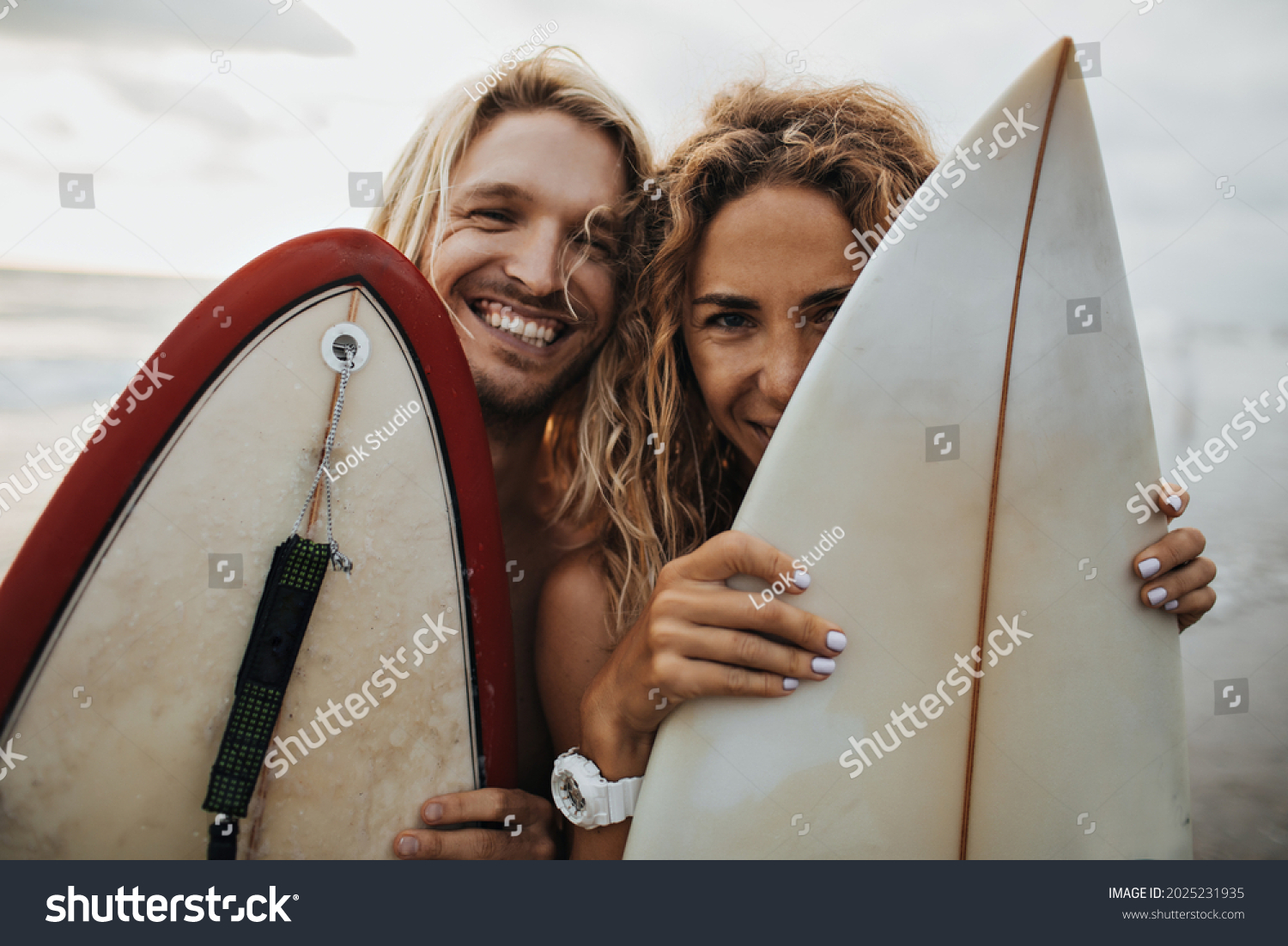 Portrait of optimistic guy and girl hiding behind surfboards #2025231935