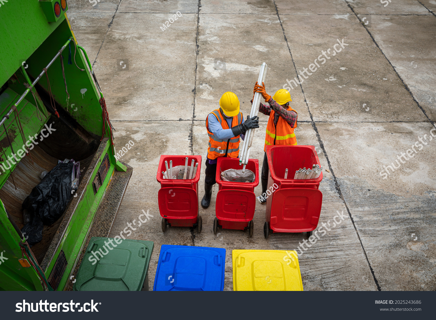 Rubbish cleaner man working with green garbage truck loading waste and trash bin at city,Waste collectors at work,Top view. #2025243686
