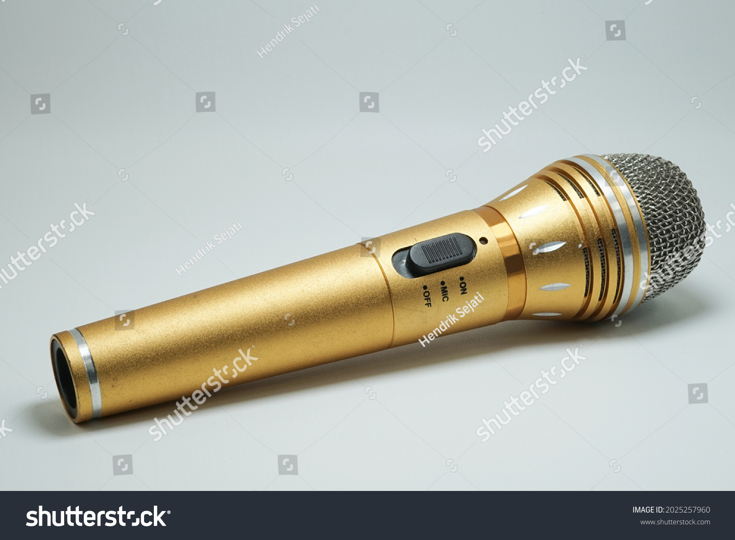 Gold microphone with chrome grille and on off switch. Gold mic on isolated white background. #2025257960