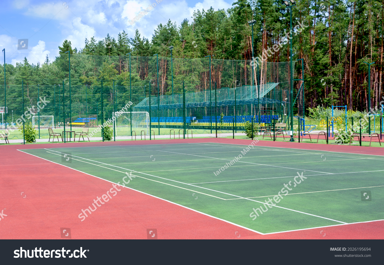 Sports ground on the outskirts of the city in a wooded area. View of the tennis court, fitness equipment, football field and others public sports grounds for team games of sport. #2026195694