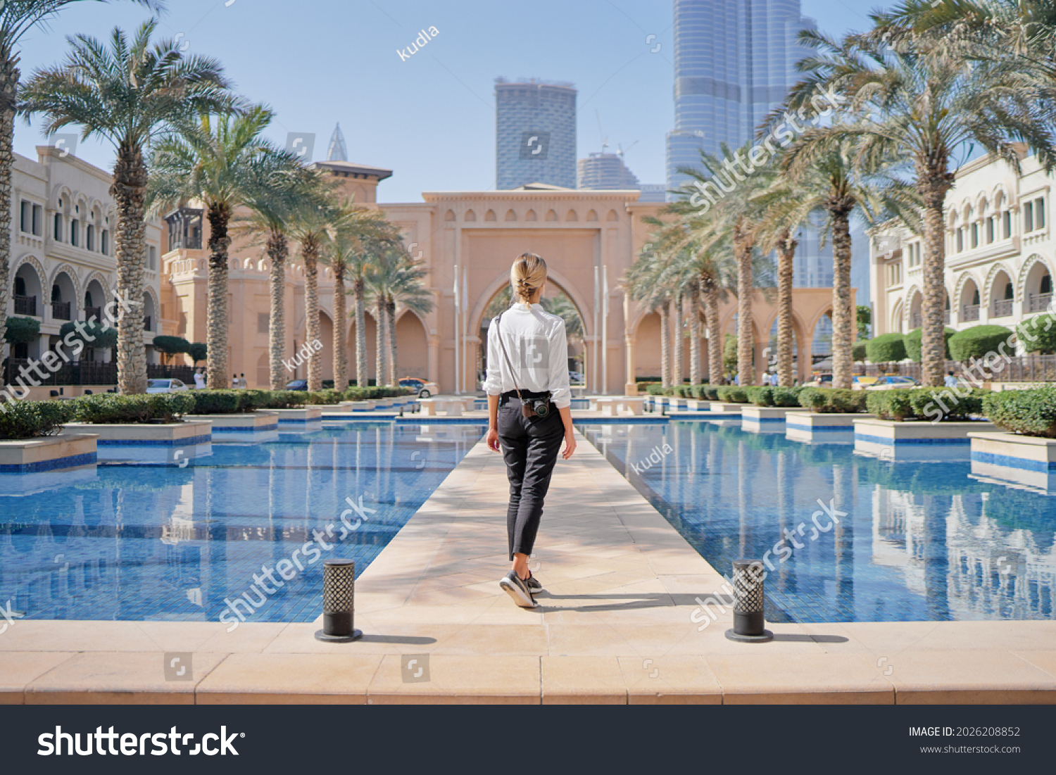Enjoying travel in United Arabian Emirates. Young woman with camera walking on Dubai Downtown. #2026208852