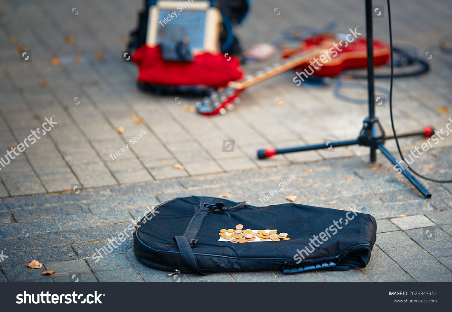 Street performers busking money. Street musician, guitar player make money. Guitar bag with coins and equipment of street musician in background.  #2026343942