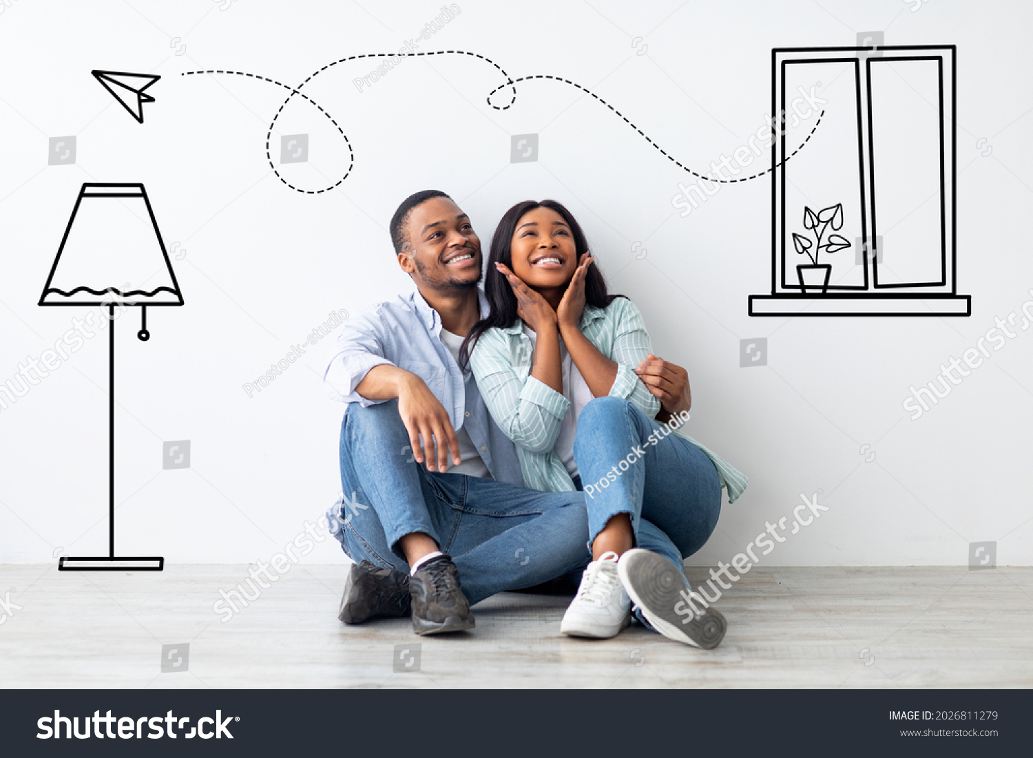 Loving african american couple imagining interior of their new apartment, embracing and sitting on floor near wall with doodle drawings, planning relocation. Creative collage #2026811279