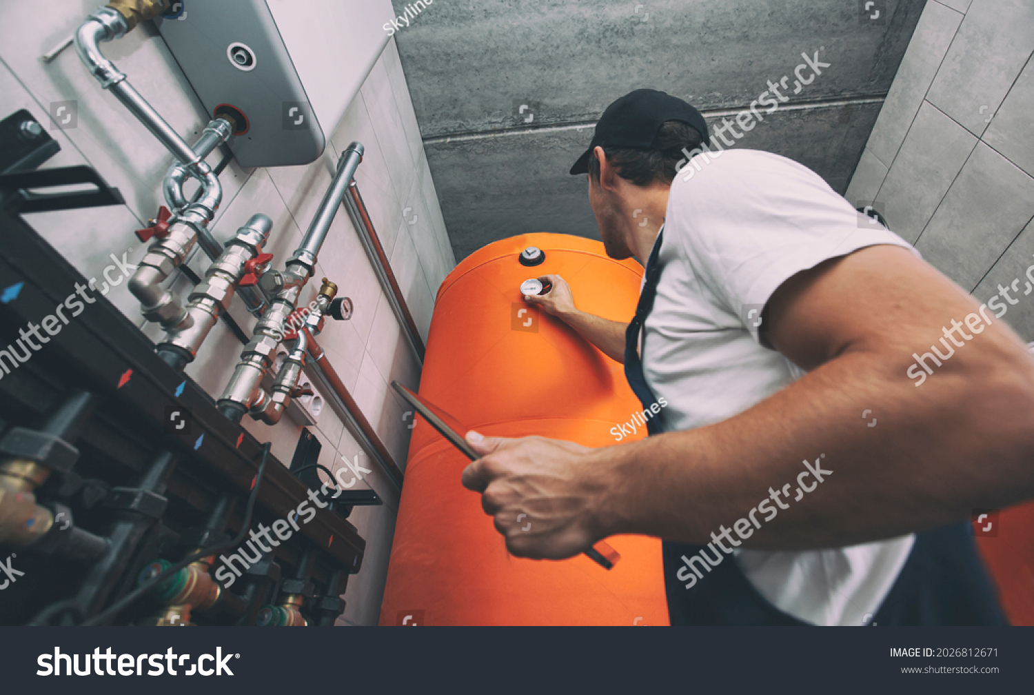 The technician checking the heating system in the boiler room with tablet in hand #2026812671