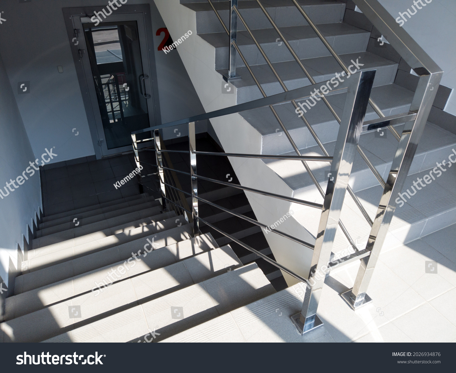 Modern stairs with metal railing in office building. Staircase with gray floor tiles. emergency exit in the shopping or business center . #2026934876