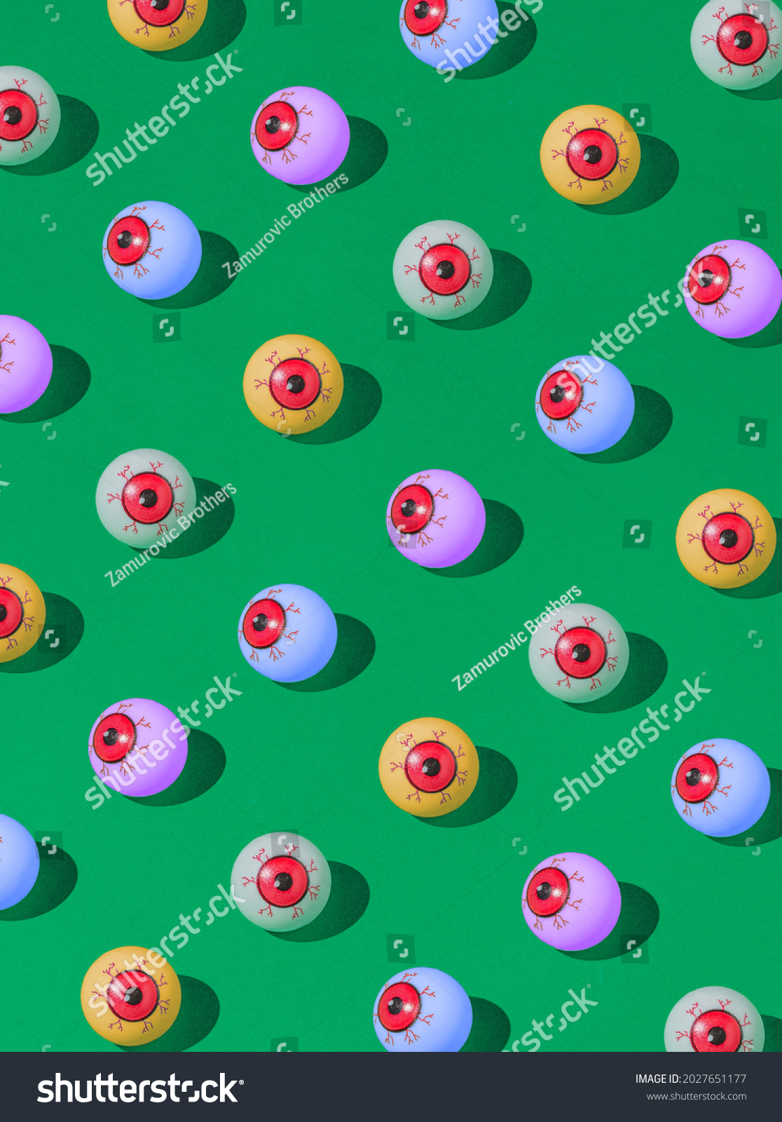 Pattern of colorful bloody eyeball Halloween candies on a vivid green background. Spooky concept. #2027651177