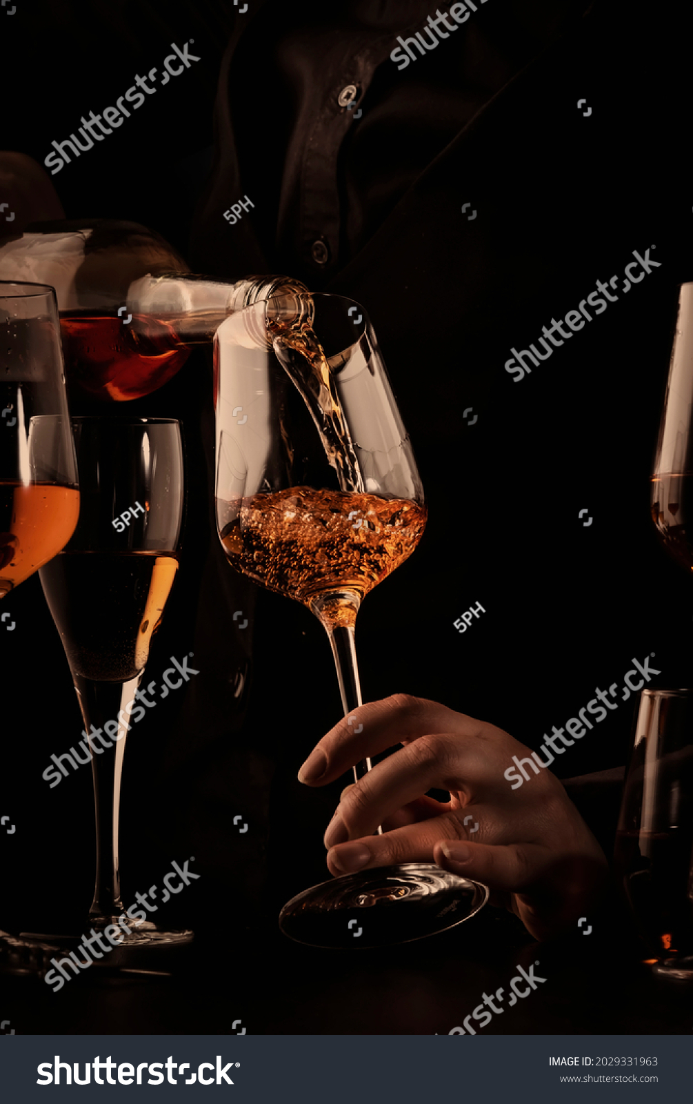 Sommelier pouring rose wine into glass at wine tasting in winery, bar or restaurant. Black toned image #2029331963