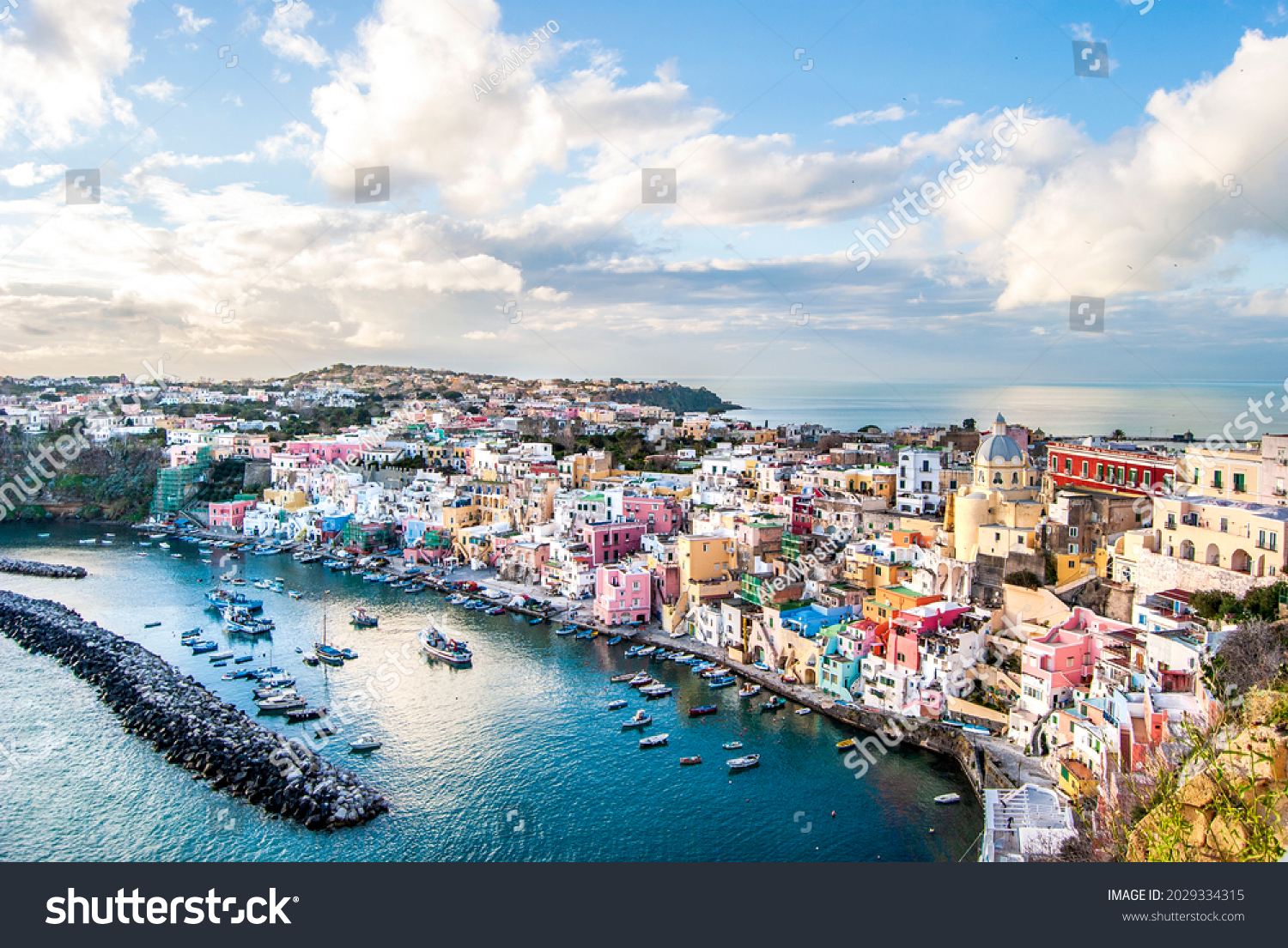 Panoramic view of Marina Corricella, a seaside fishing village in Procida island, with colorful buildings, harbor and boats, in Procida Island, province of Naples, Italy #2029334315