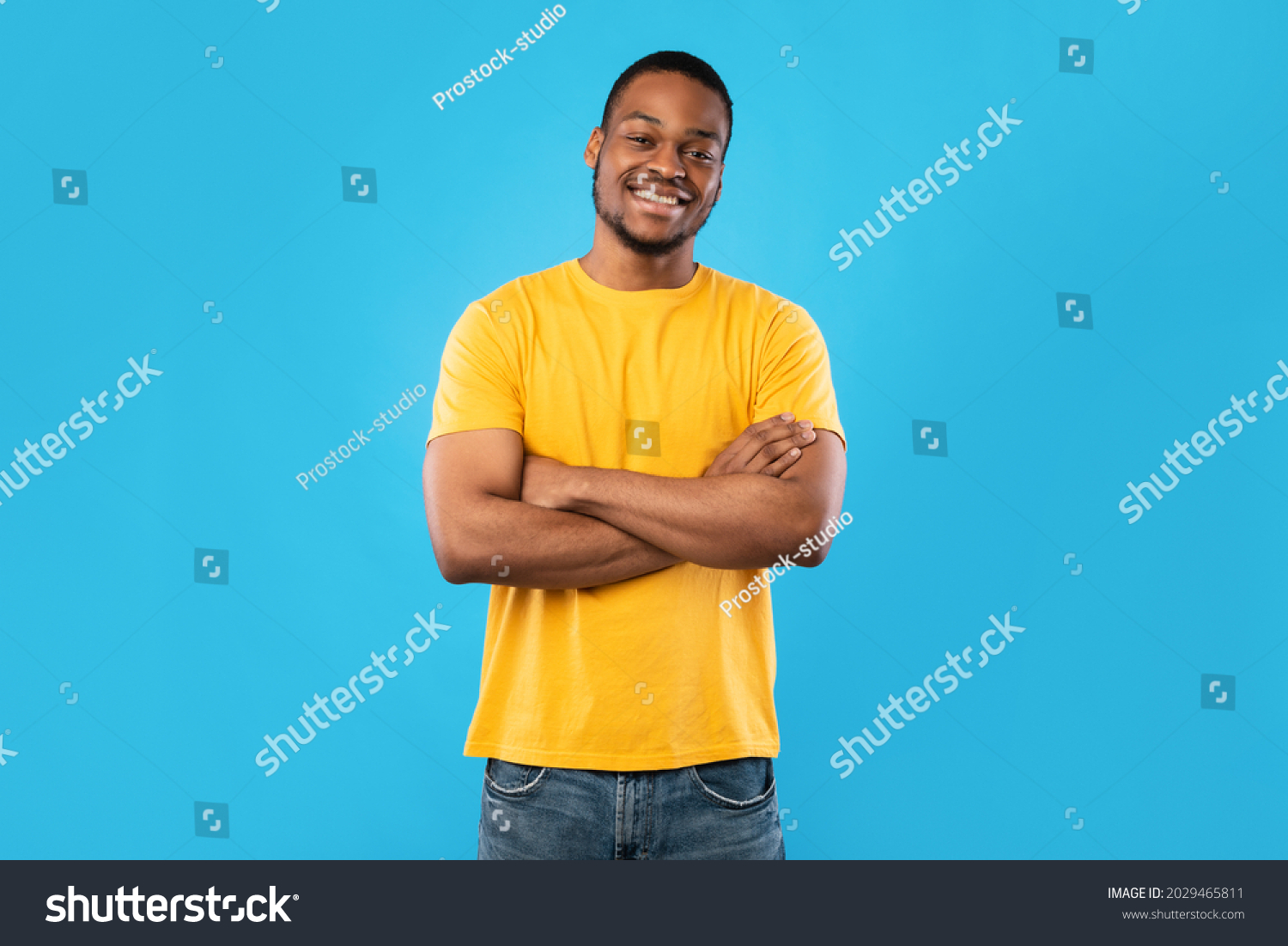 Cheerful African American Guy Smiling To Camera Posing Crossing Hands Standing Over Blue Background. Studio Shot Of Happy Self-Confident Black Millennial Man Expressing Positive Emotions #2029465811