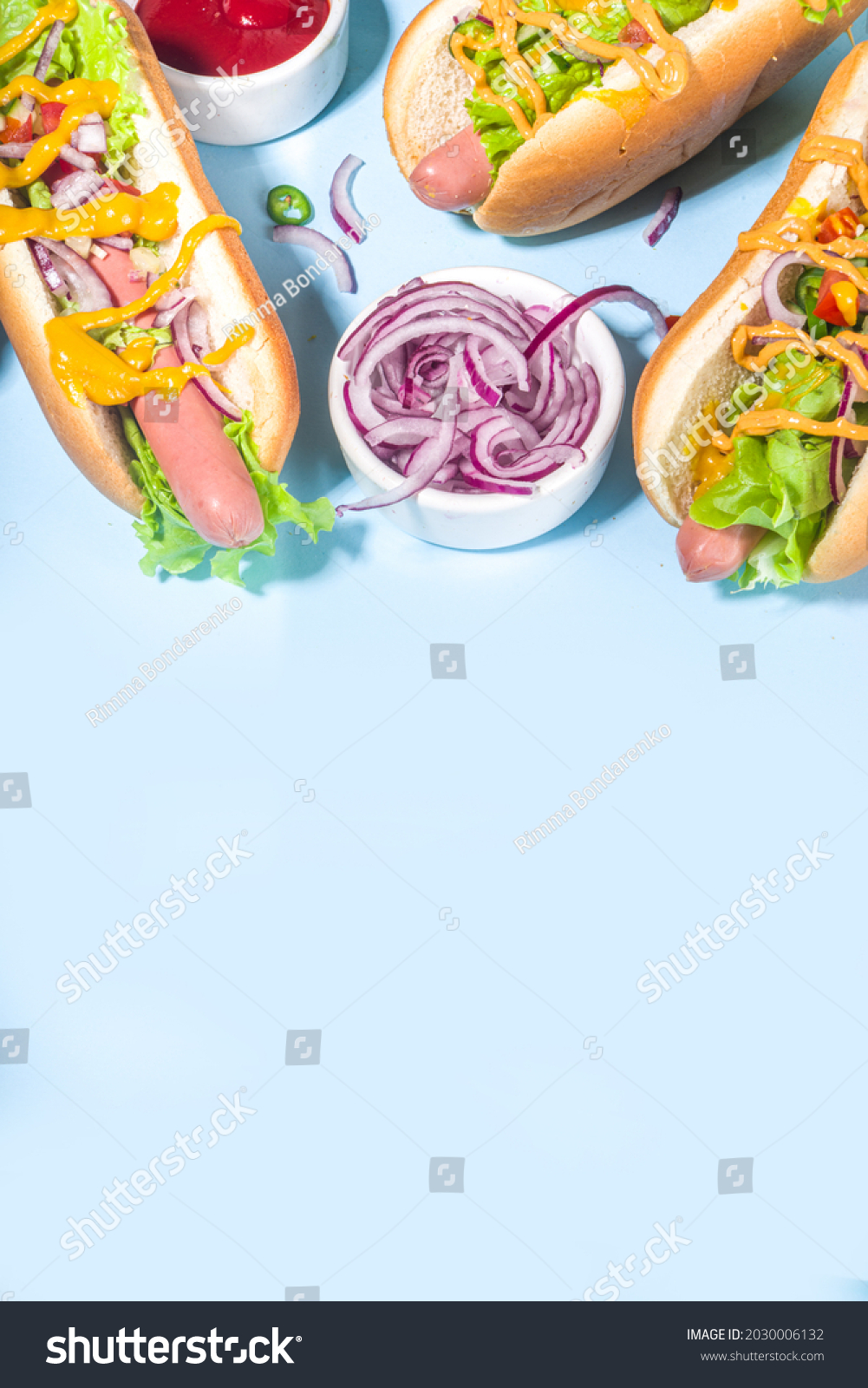 Barbecue grilled fastfood, Various traditional american hot dogs set with sausage, yellow mustard, ketchup and fresh vegetables salad, top view on bright blue background with french fries #2030006132