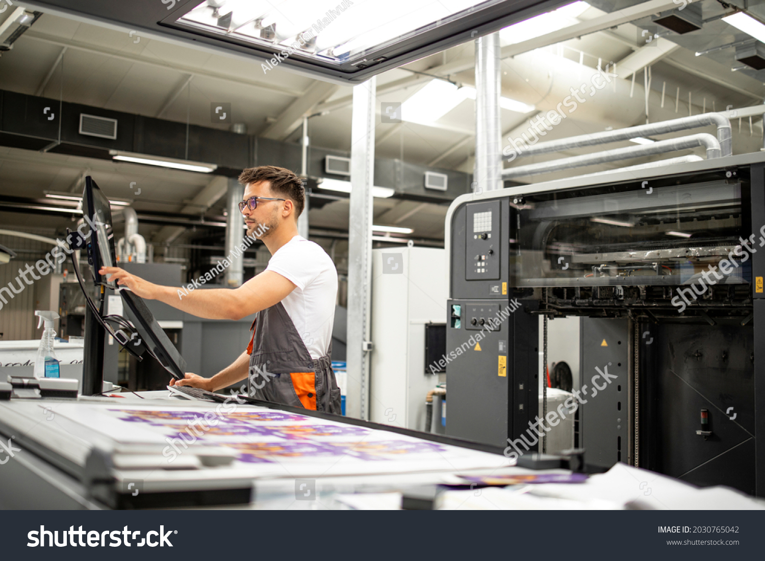 Print house worker setting parameters on modern offset printing machine. #2030765042