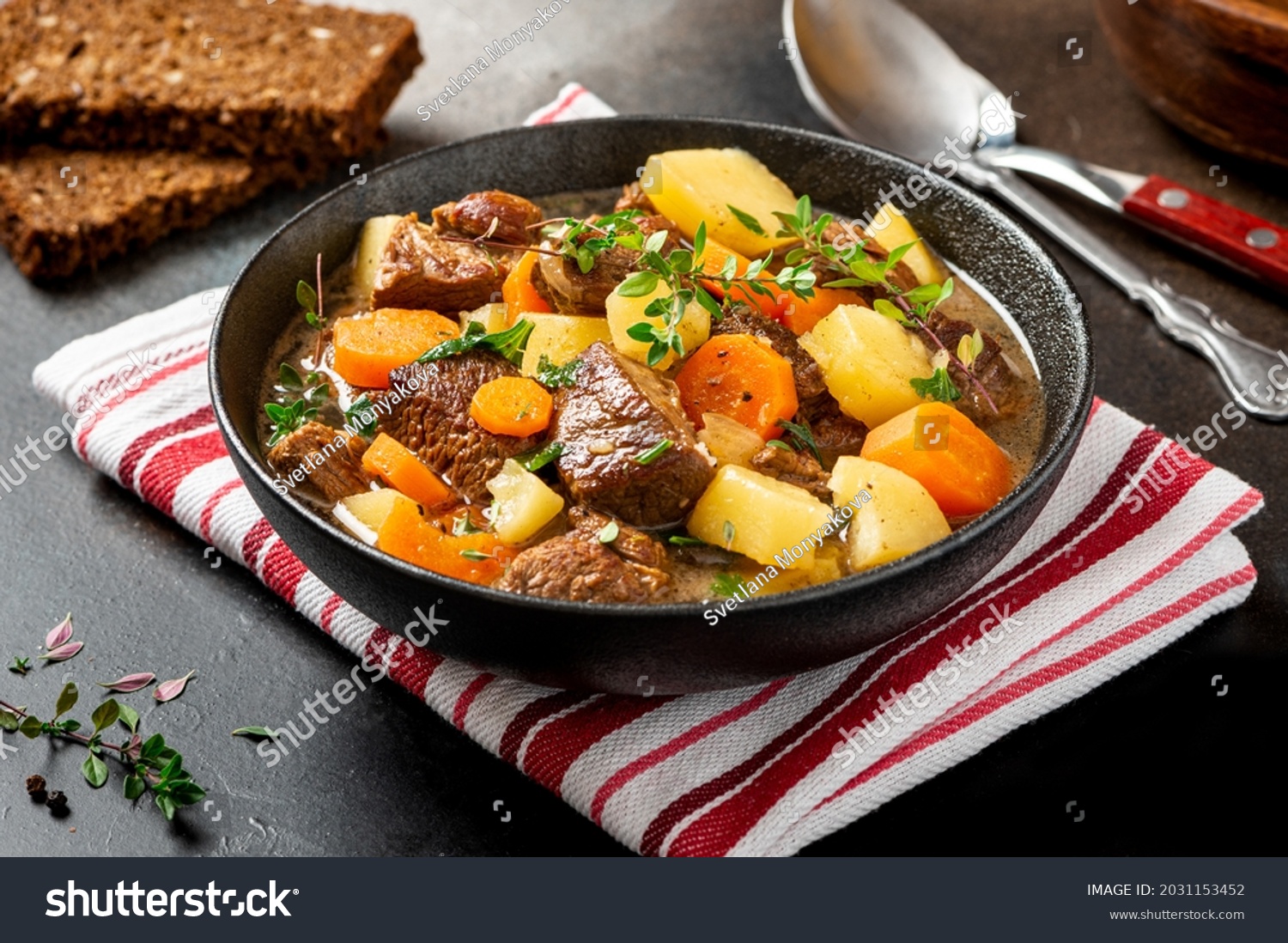 Traditional Irish stew in a black bowl on a dark background. Stew of lamb, potatoes, onions, carrots, and thyme. Traditional dish of St. Patrick's Day. #2031153452