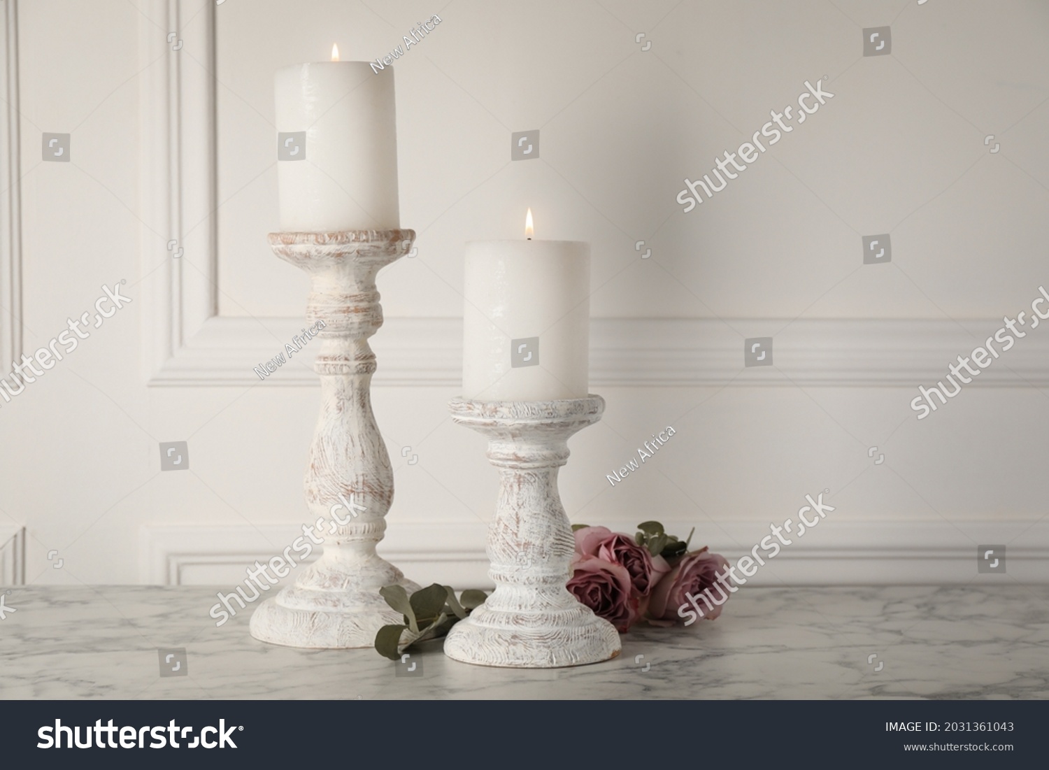 Elegant candlesticks with burning candles and flowers on white marble table #2031361043
