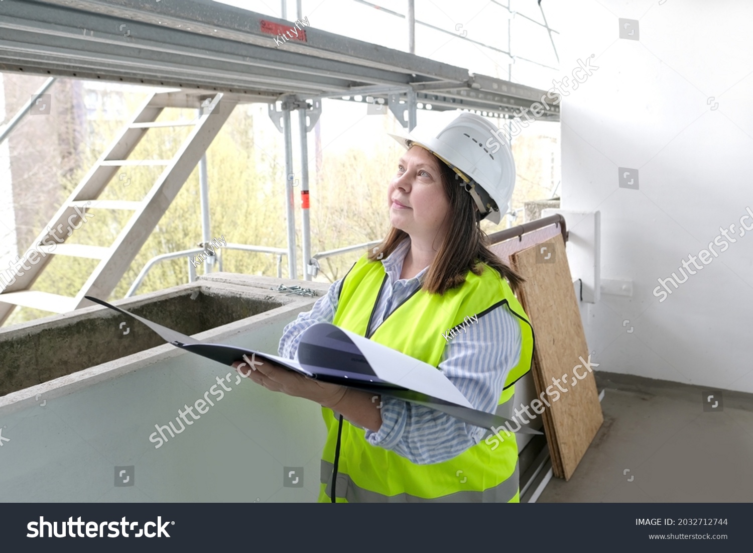 experienced woman architect, constructor engineer in protective white helmet controls the object at the construction site for the renovation of buildings, civil engineering concept #2032712744
