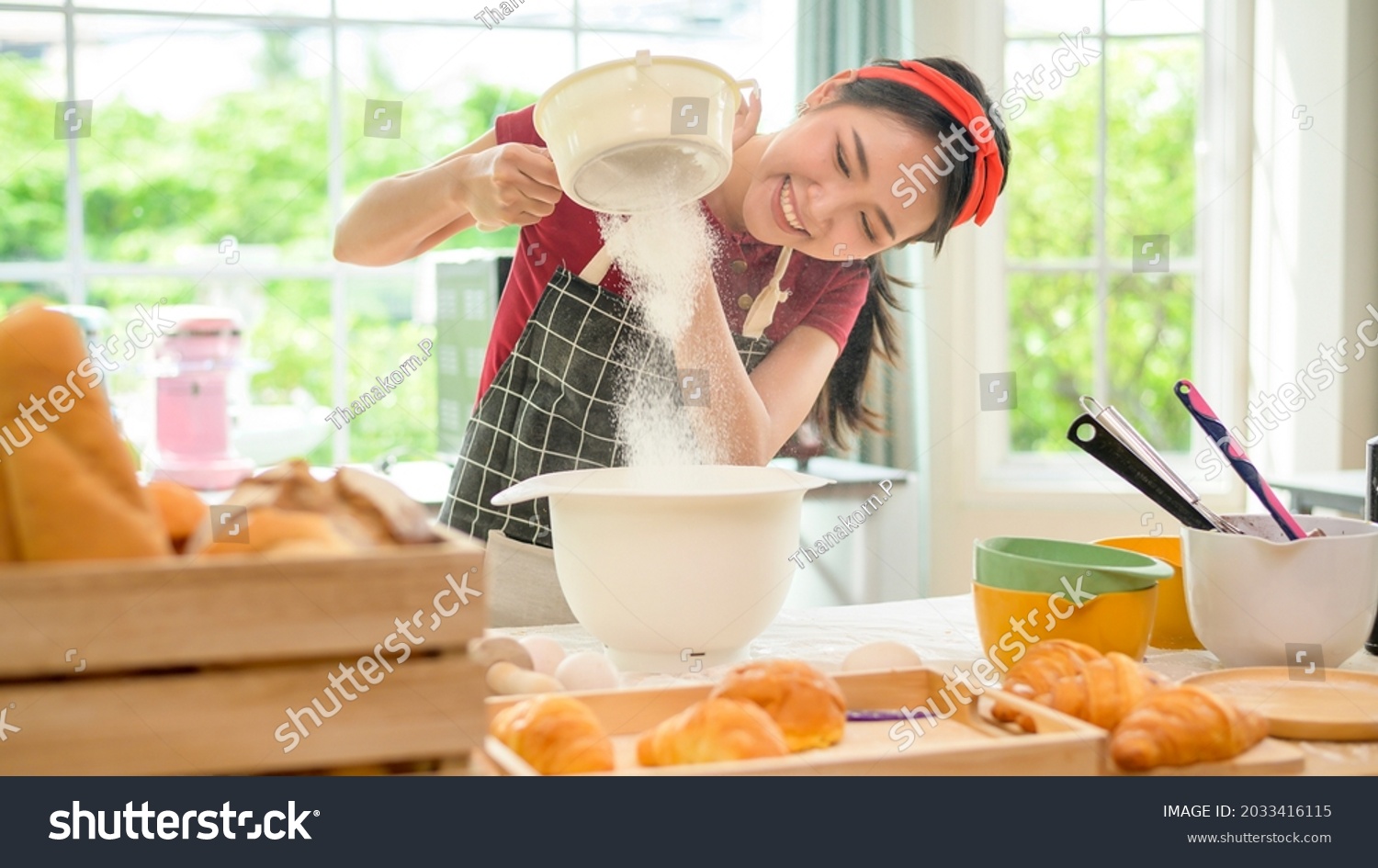 A young beautiful Asian woman is baking in her kitchen  , bakery and coffee shop business  #2033416115