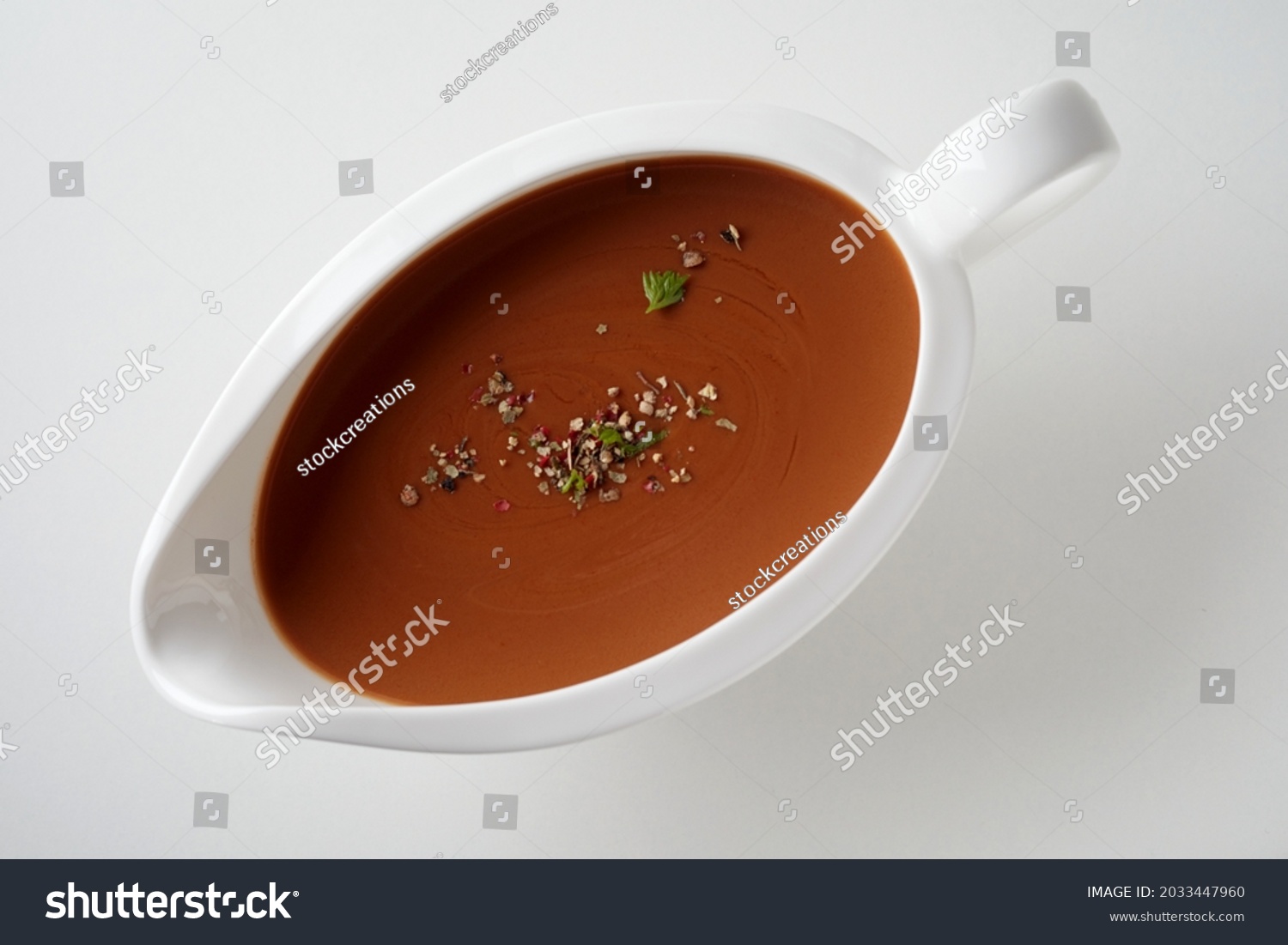 Top view of brown sauce with herbs and spices in ceramic gravy boat place on white surface #2033447960