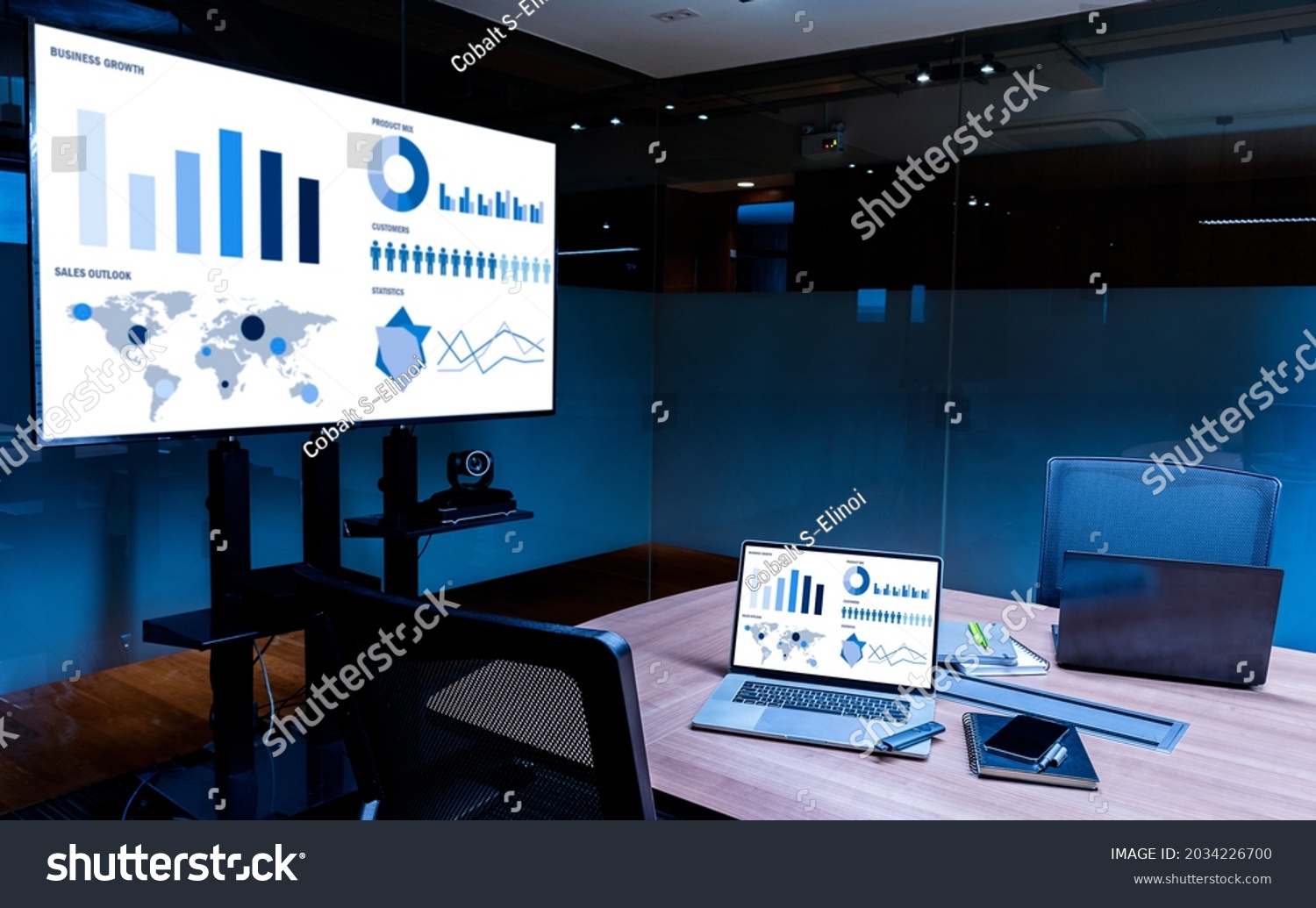 Mock up sales summary slide show presentation on display television and laptop with notebook on table in meeting room #2034226700