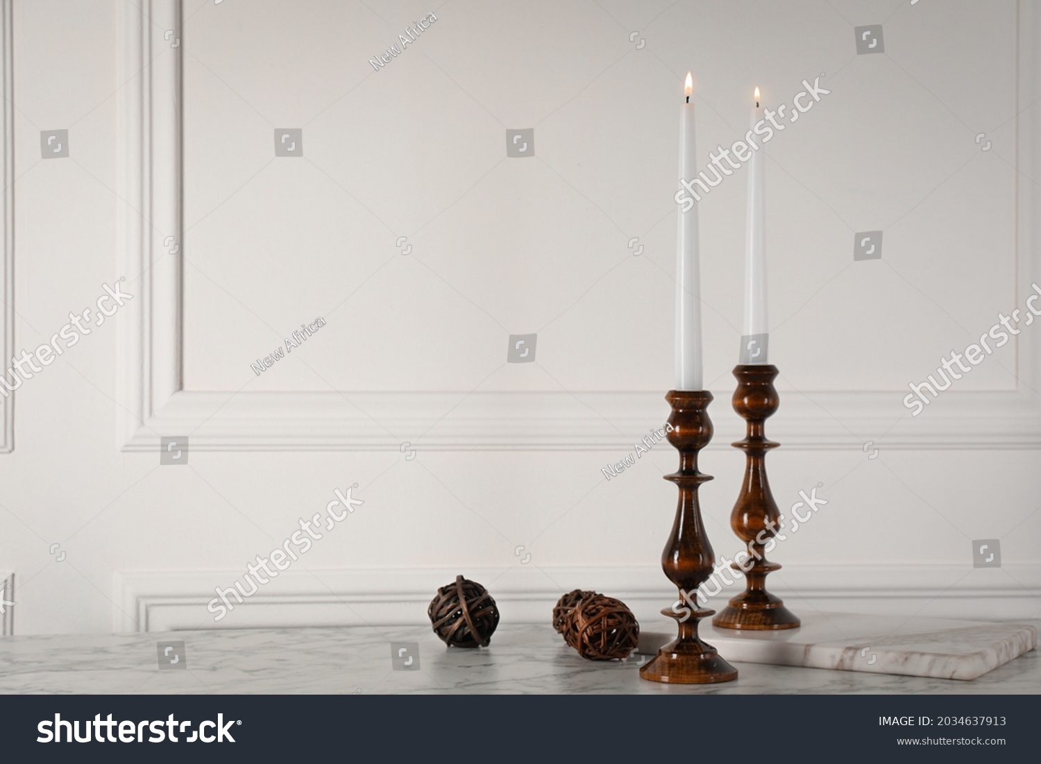 Elegant candlesticks with burning candles on white marble table. Space for text #2034637913