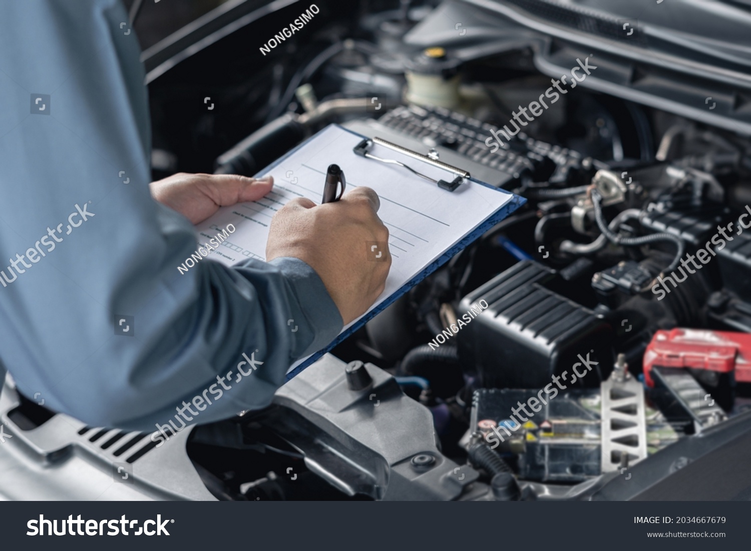 Close up hand car service staff check engine malfunctions and mistake check list in engine room : Car service concept   #2034667679
