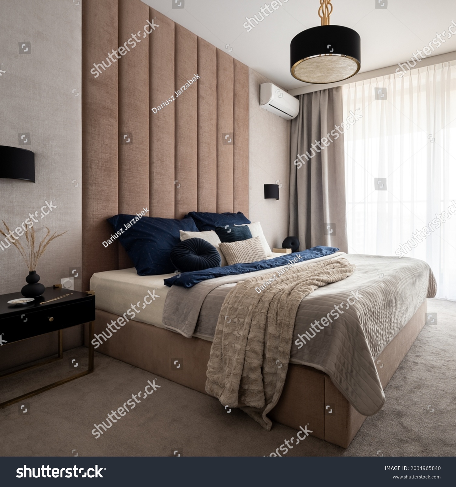 Elegant and classy bedroom with big window, big and comfortable bed with upholstered wall, nice bedclothes, black bedside table and lamps and carpet floor #2034965840