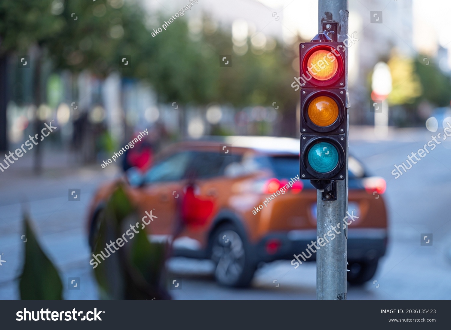 blurred view of city traffic with traffic lights, in the foreground a semaphore with a red light #2036135423