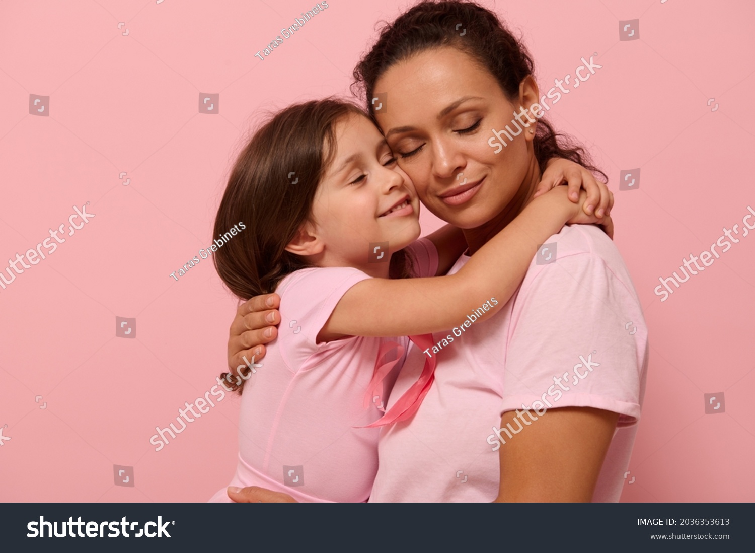 Beautiful loving mother and daughter, hugging each other, wearing pink clothes with a pink ribbon, symbol of World Breast Cancer awareness Day in October. World Cancer Day national Cancer Survivor Day #2036353613