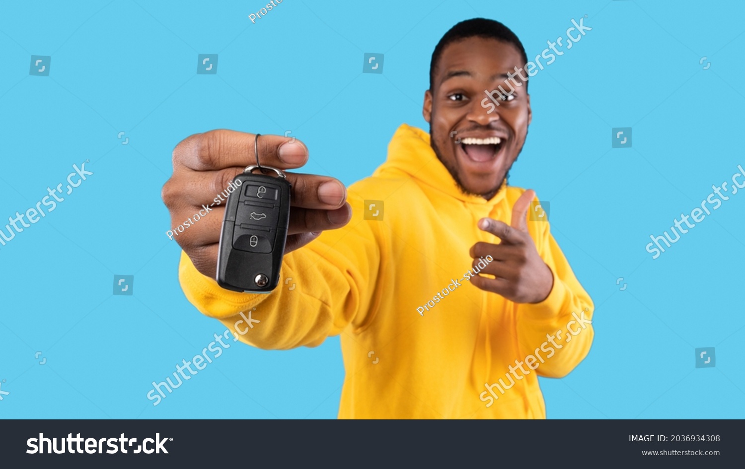New Car. Excited Black Man Showing Key In Excitement Celebrating Buying New Auto Posing Standing On Blue Studio Background. Dreams Come True, Own Automobile Concept. Panorama, Selective Focus #2036934308