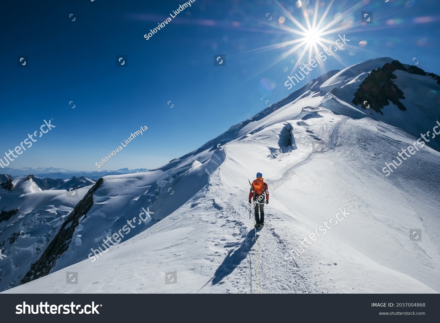 Before Mont Blanc (Monte Bianco) summit 4808m last ascending. Team roping up Man with climbing axe dressed high altitude mountaineering clothes with backpack walking by snowy slopes with blue sky. #2037004868