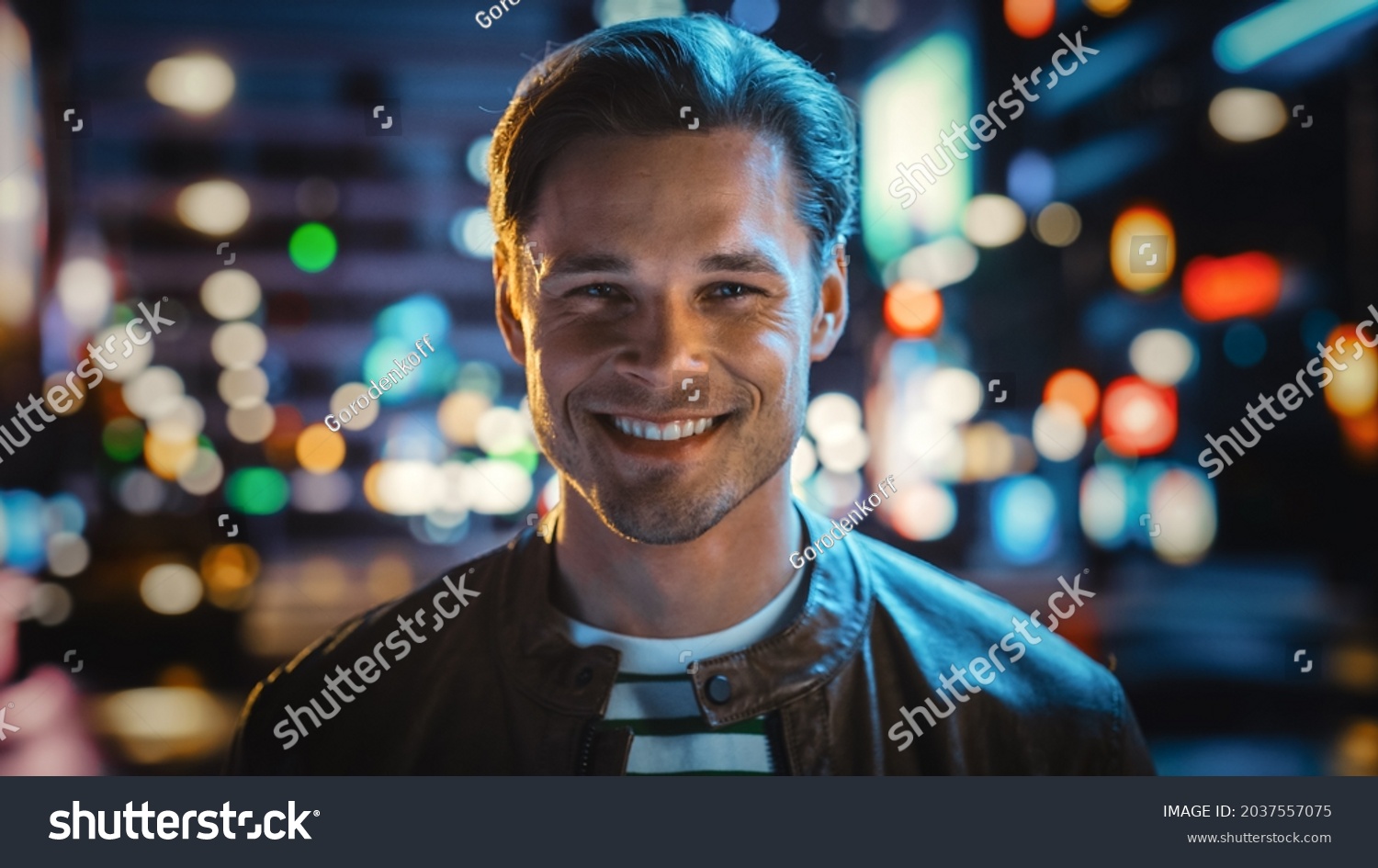 Portrait of Handsome Blonde Man Smiling, Looking at Camera, Standing in Night City with Bokeh Neon Street Lights in Background. Happy Confident Young Man with Stylish Hair. Close-up Portrait #2037557075