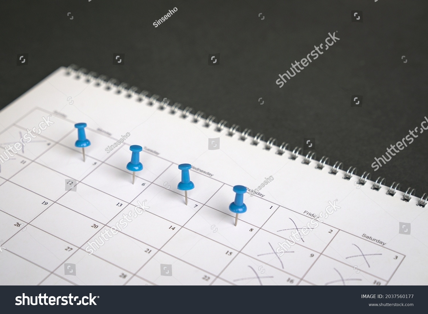 Blue pins on four days in a week on a calendar. Friday, Saturday and Sunday crossed out. Four day work week concept. #2037560177