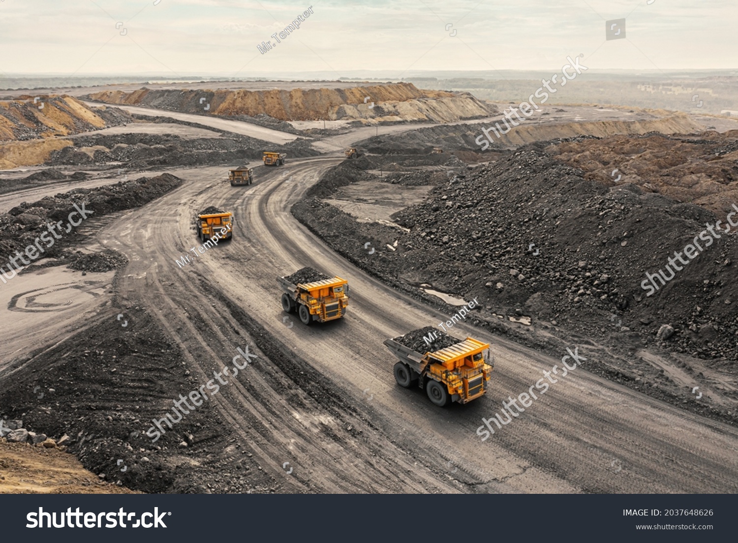 Large quarry dump truck. Big yellow mining truck at work site. Loading coal into body truck. Production useful minerals. Mining truck mining machinery to transport coal from open-pit production #2037648626