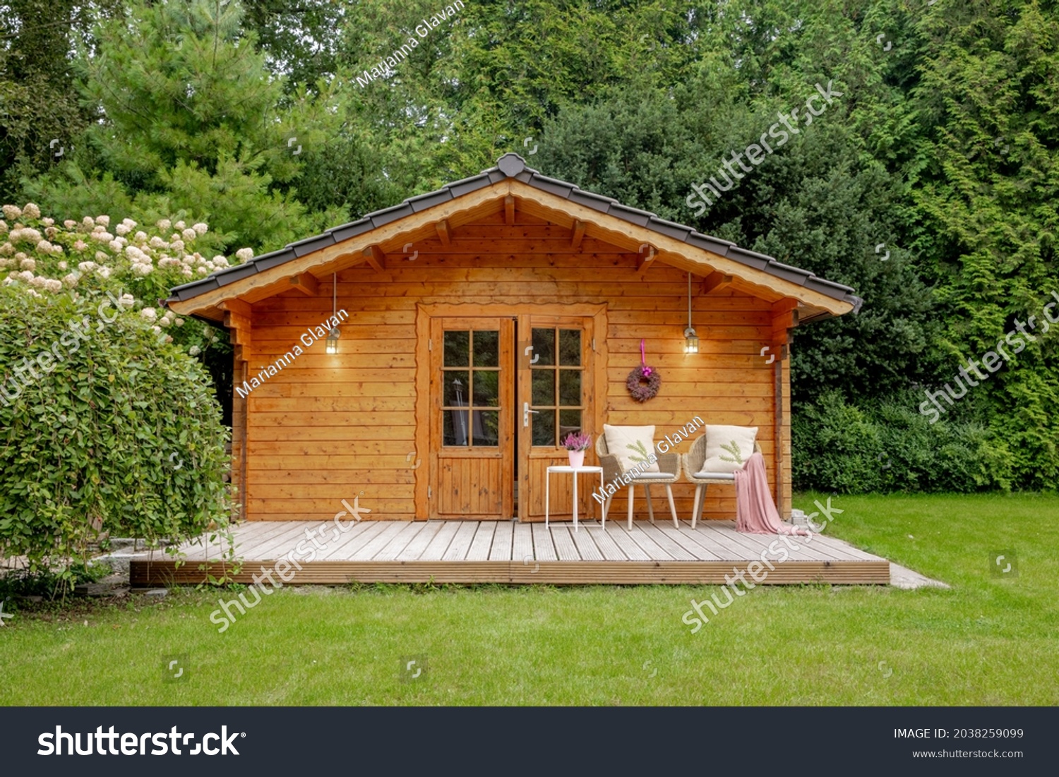 Wooden garden shed with two chairs outside. Wooden house with a large garden and a white panicle hydrangea  #2038259099