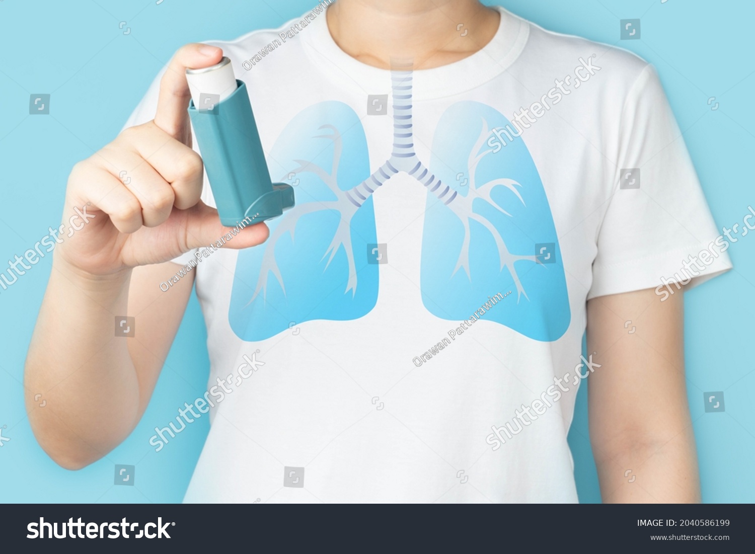 Young woman using blue asthma inhaler for relief asthma attack. Pharmaceutical products is used to prevent and treat wheezing and shortness of breath caused asthma or COPD. Lung organ anatomy. #2040586199