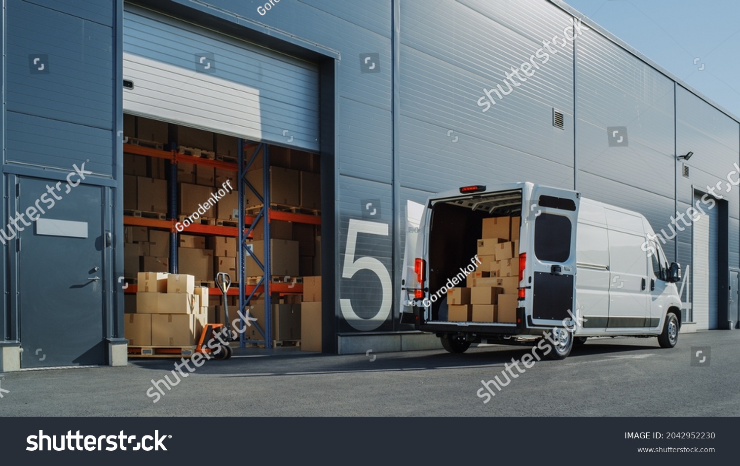 Outside of Logistics Warehouse with Open Door, Delivery Van Loaded with Cardboard Boxes. Truck Delivering Online Orders, Purchases, E-Commerce Goods, Wholesale Merchandise. #2042952230