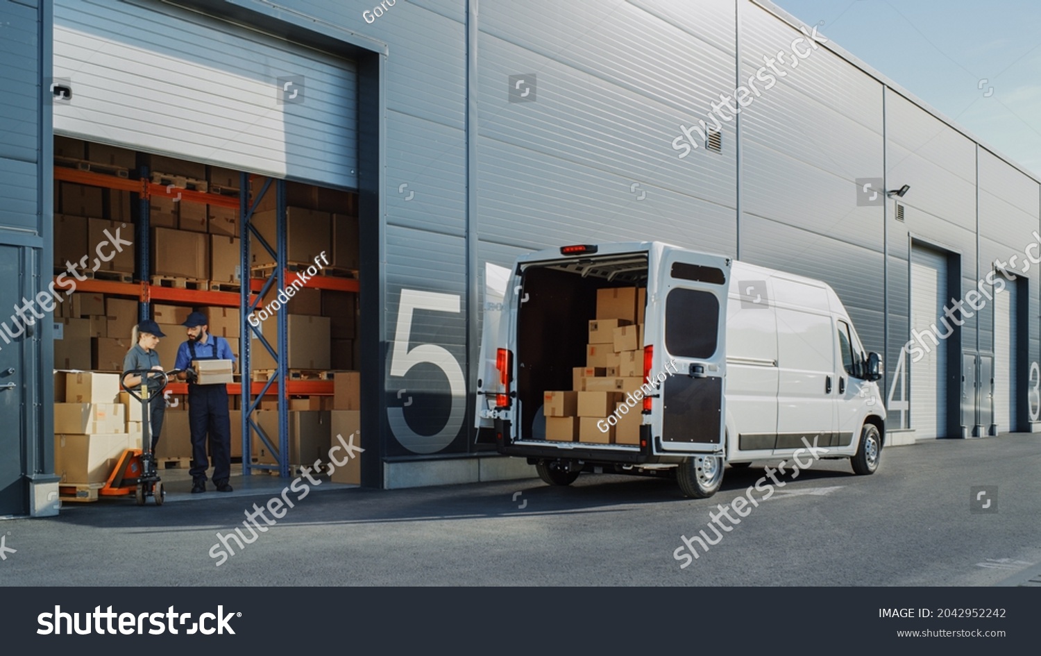 Outside of Logistics Warehouse with Open Door, Delivery Van Loaded with Cardboard Boxes. Truck Delivering Online Orders, Purchases, E-Commerce Goods, Wholesale Merchandise. #2042952242
