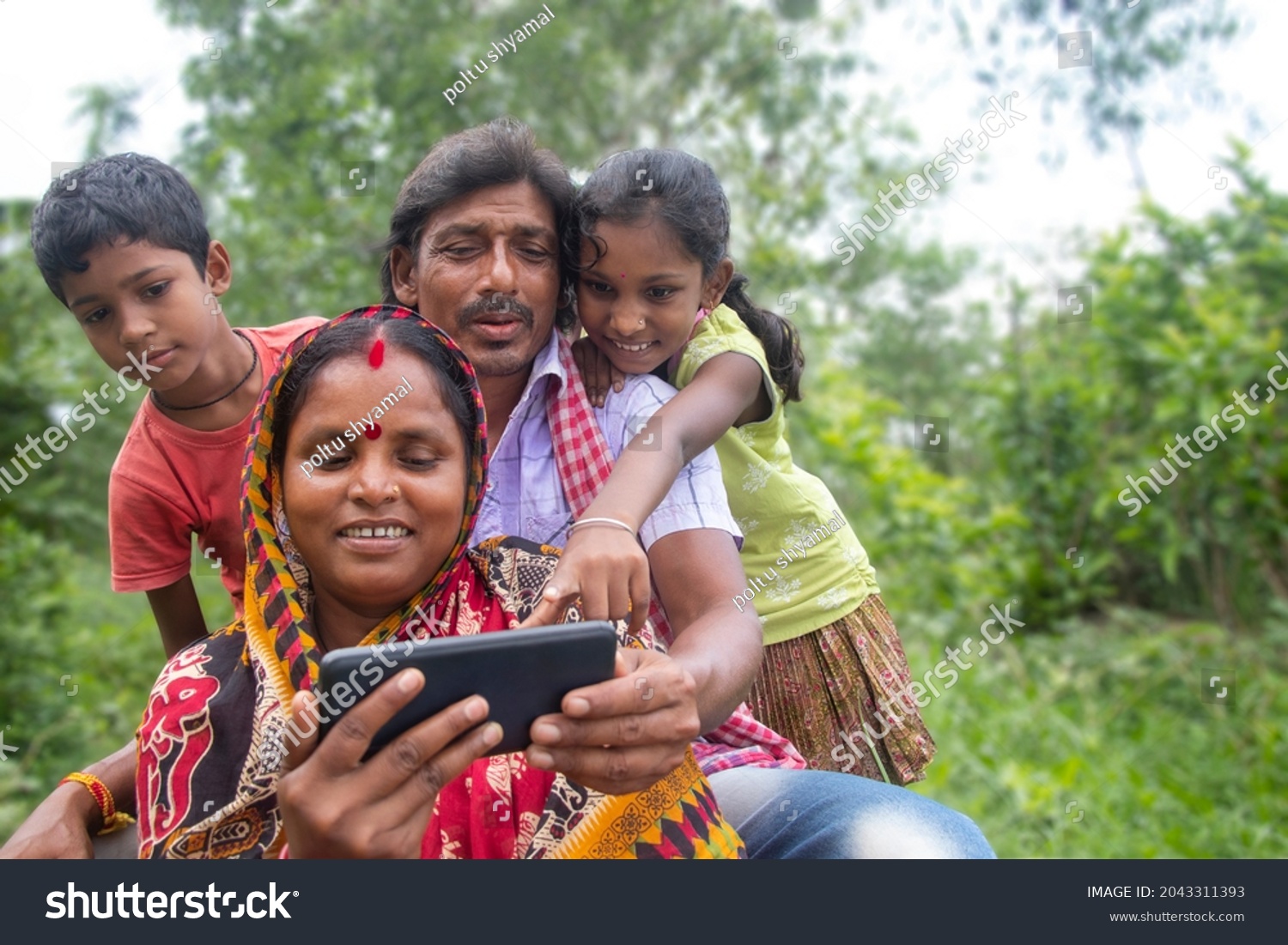 Indian Rural Parents and their two children watching movie in agricultural field #2043311393