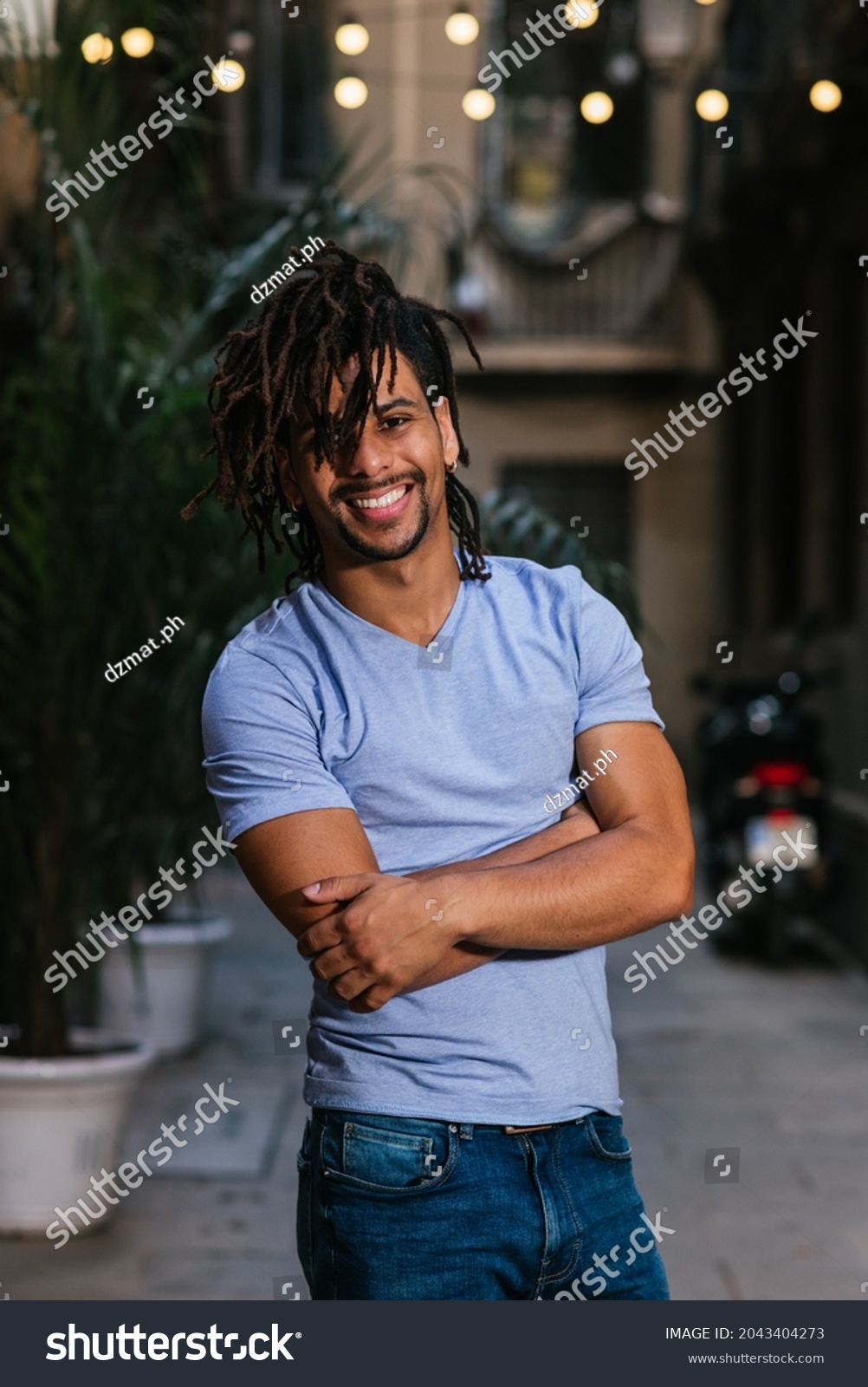 vertical portrait of an hispanic young man with dreadlocks. He is looking at camera and smiles #2043404273