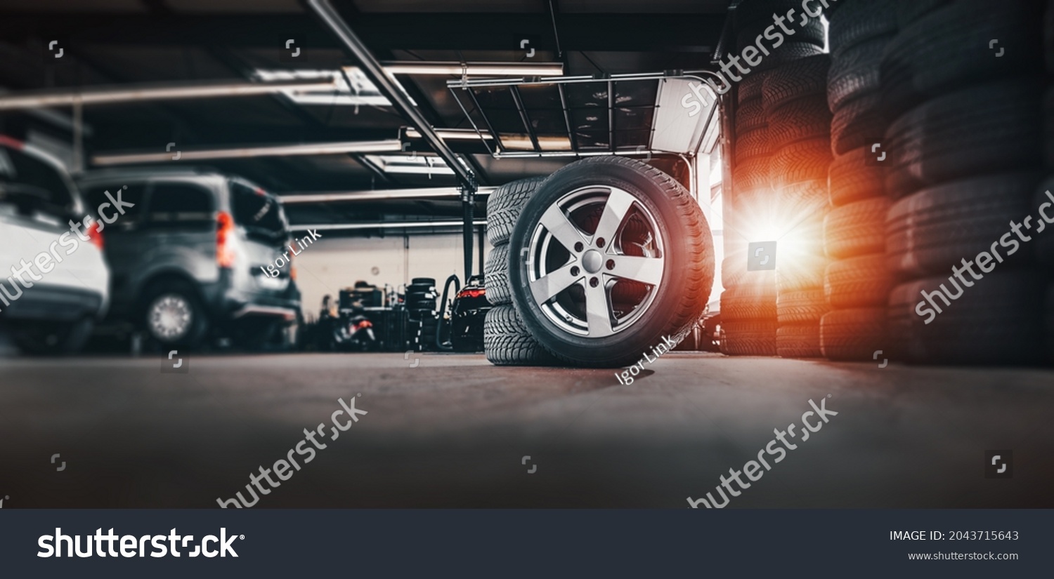 tire at repairing service garage background. Technician man replacing winter and summer tyre for safety road trip. Transportation and automotive maintenance concept  #2043715643