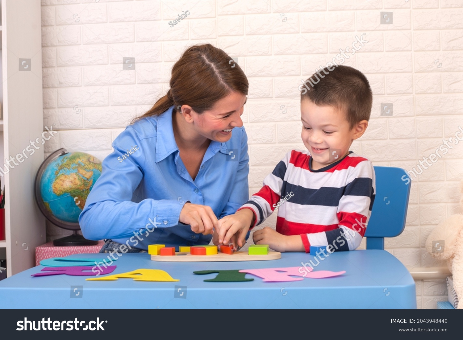 Toddler boy in child occupational therapy session doing sensory playful exercises with her therapist. #2043948440