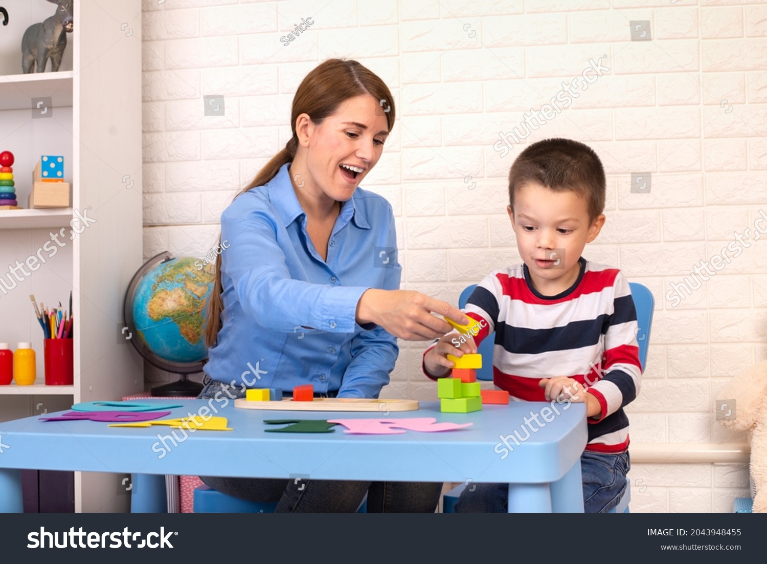 Toddler boy in child occupational therapy session doing sensory playful exercises with her therapist. #2043948455