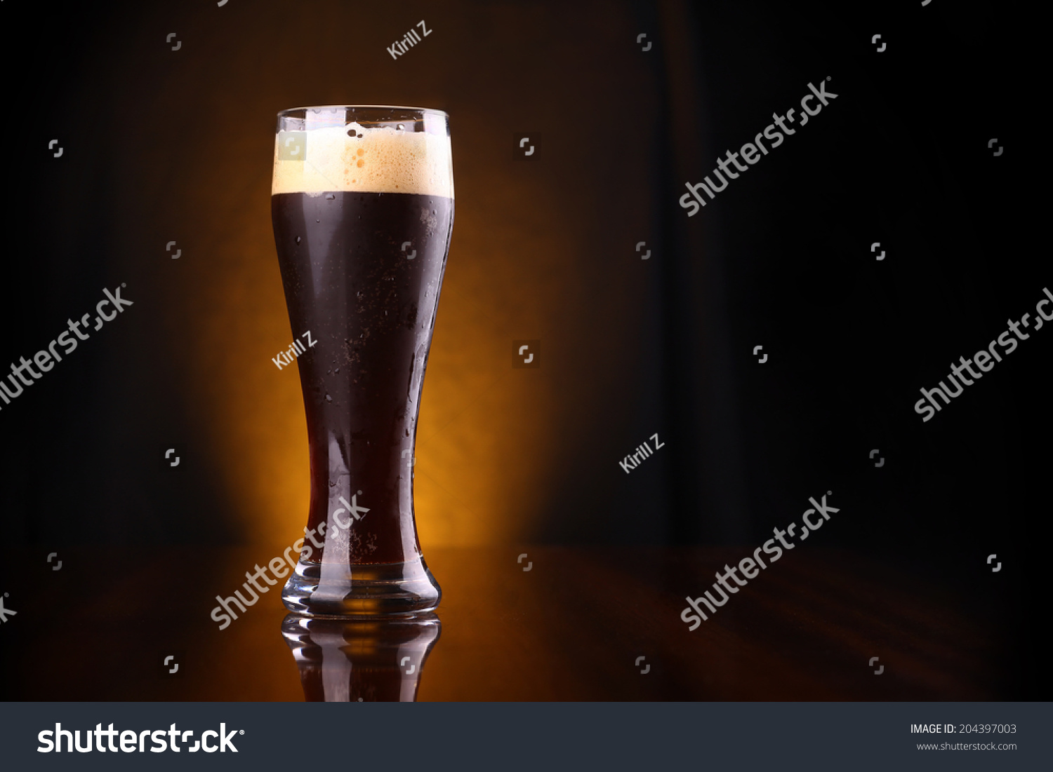 Tall glass of dark beer over a dark background lit yellow #204397003