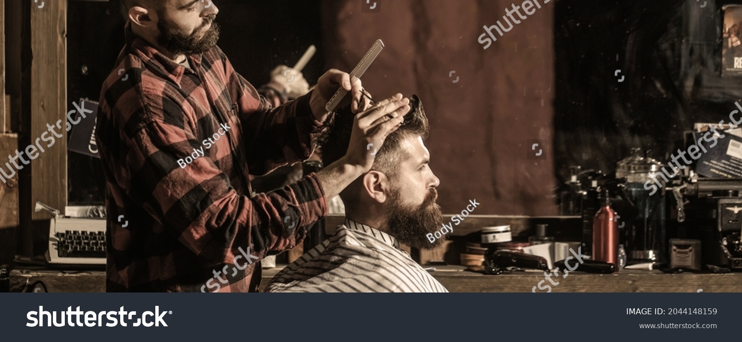 Hairstylist serving client at barber shop. Man visiting hairstylist in barbershop. Bearded man in barbershop. Work in the barber shop. Man hairstylist. #2044148159