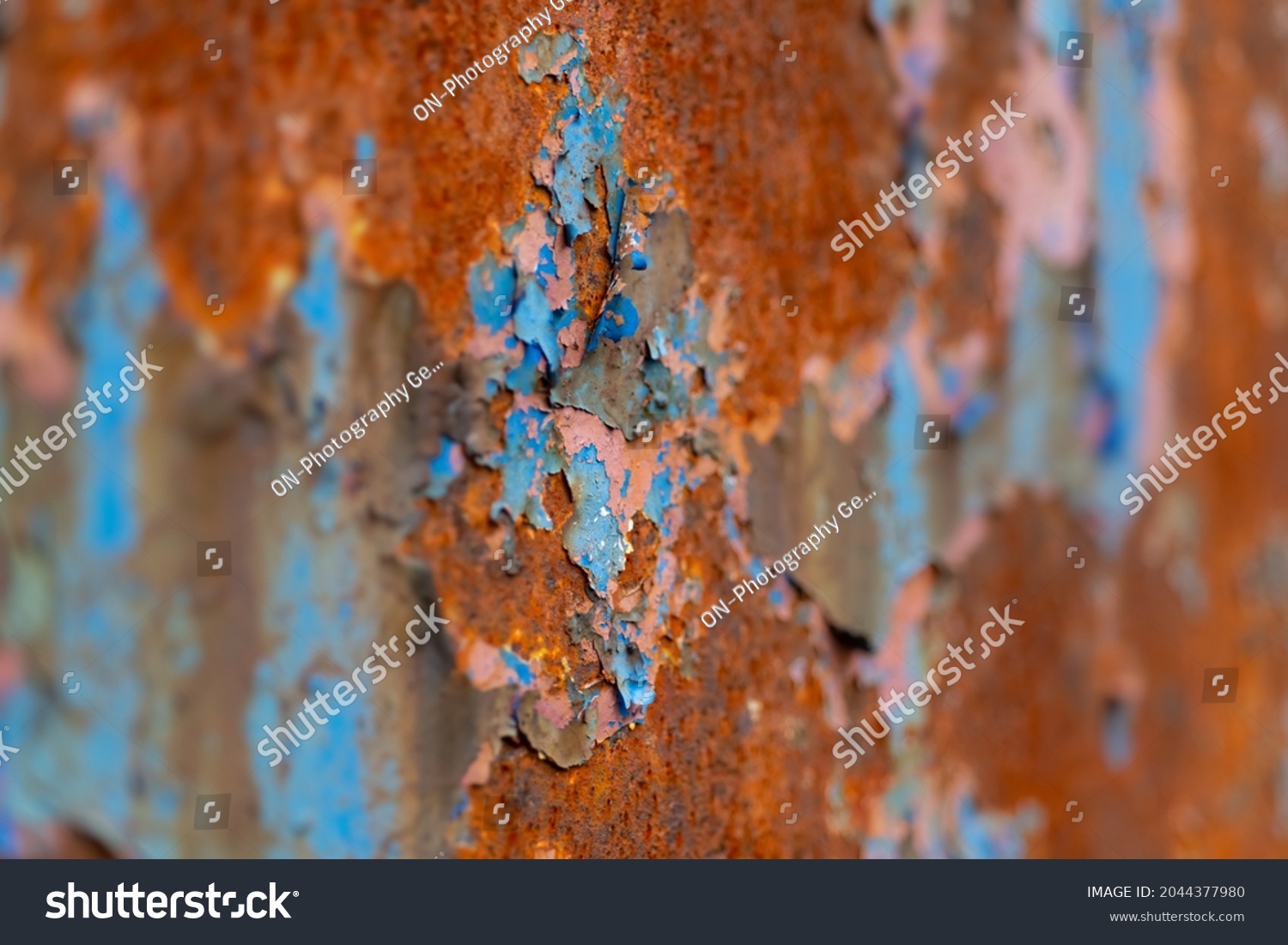 Peeled off paint on rusty vehicle surface of a ruined train. Vintage metal background with wheathered rotten color and massive corrosion in shades of blue, brown and turqouise with selective focus. #2044377980